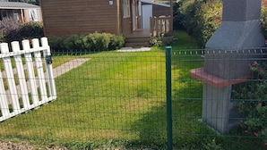 A wooden house with a small porch and a fenced yard.
