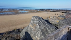 A beach with large rocks in the foreground and a sandy shore extending to the ocean.
