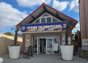 Un edificio con un cartel que dice 'OFFICE DE TOURISME' y un cielo despejado arriba.