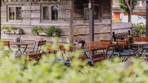 Un espace extérieur aménagé avec des tables et des chaises en bois, un mur en pierre et des plantes en pot.