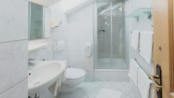 A modern bathroom with a sink, toilet, and glass-enclosed shower.