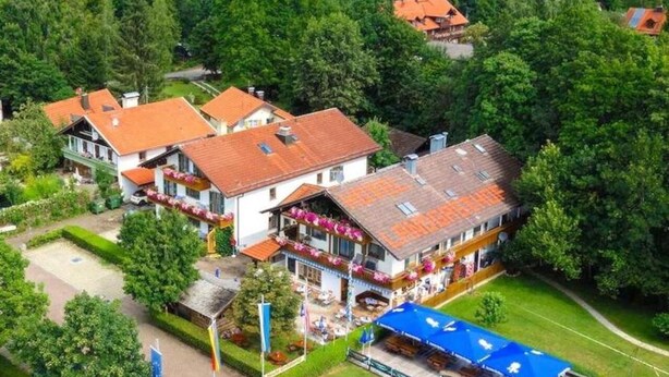 Un village au bord d’un lac, doté d’une architecture traditionnelle, avec un bâtiment central orné d’un balcon et offrant une vue sur le lac.