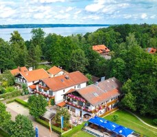 A lakeside village with traditional architecture, a central building with a balcony, and a view of the lake.