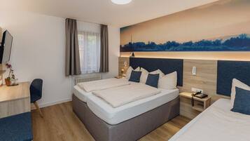 A modern hotel room with a large bed, a desk, and a painting of a landscape on the wall.