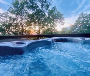 A hot tub with a view of trees and a sunset. - Luxury Lake Cottage, perfect location by land & water on amazing property. (Lake Hamilton)