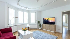 A modern living room with a red sofa, white coffee table, and a TV on a wooden cabinet. - Altes Rathaus Hahnenklee (Goslar)