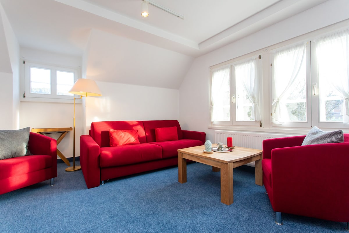 A room with a red sofa, a wooden coffee table, and a floor lamp.