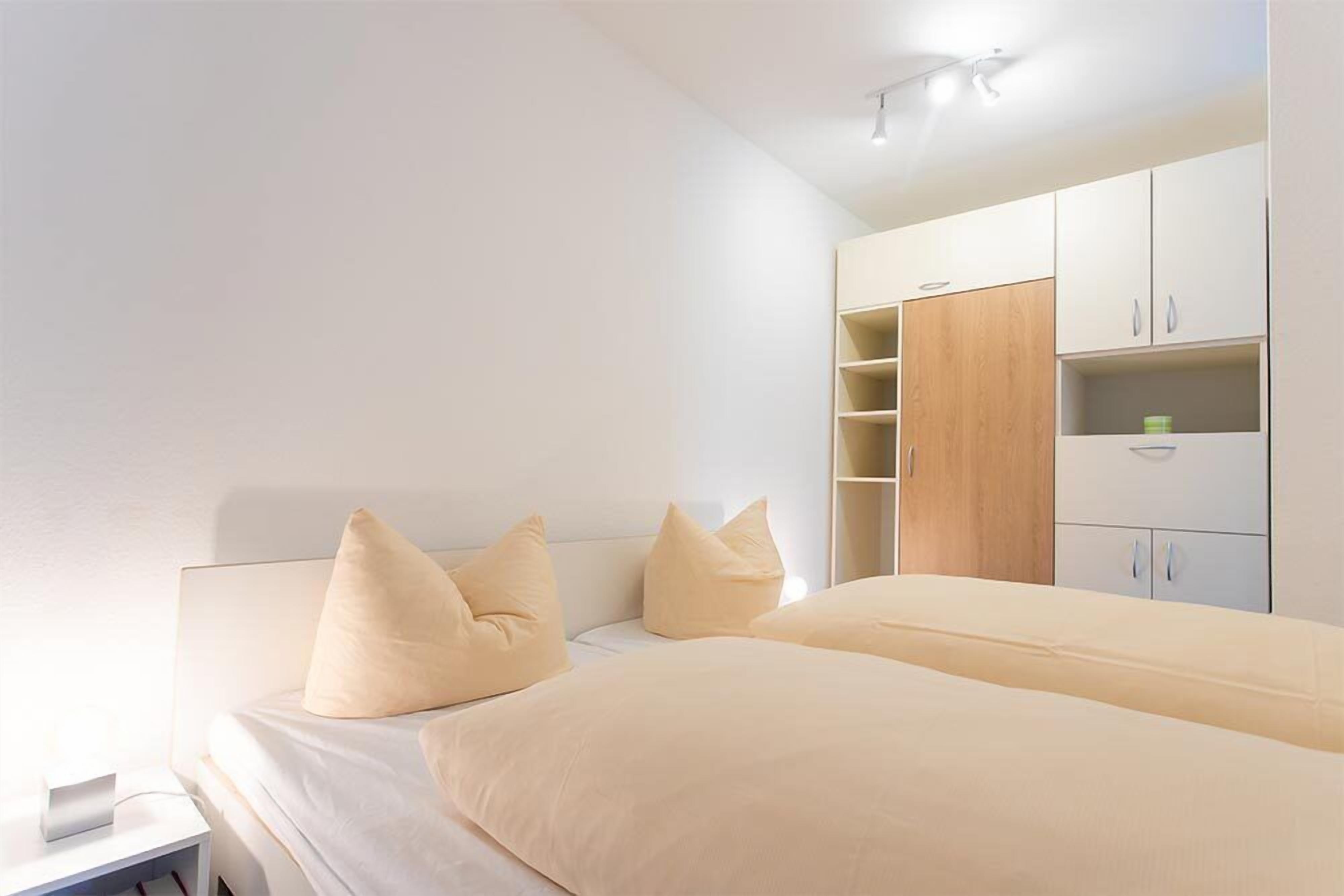 Een slaapkamer met twee bedden, een nachtkastje en een open kledingkast.