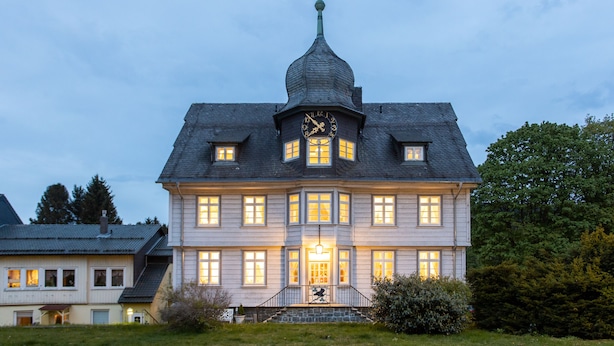 A large, historic building with a prominent clock tower and multiple windows. - Altes Rathaus Hahnenklee (Goslar)