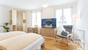 A modern hotel room with a bed, a desk with a TV, a chair, and a plant. - Altes Rathaus Hahnenklee (Goslar)