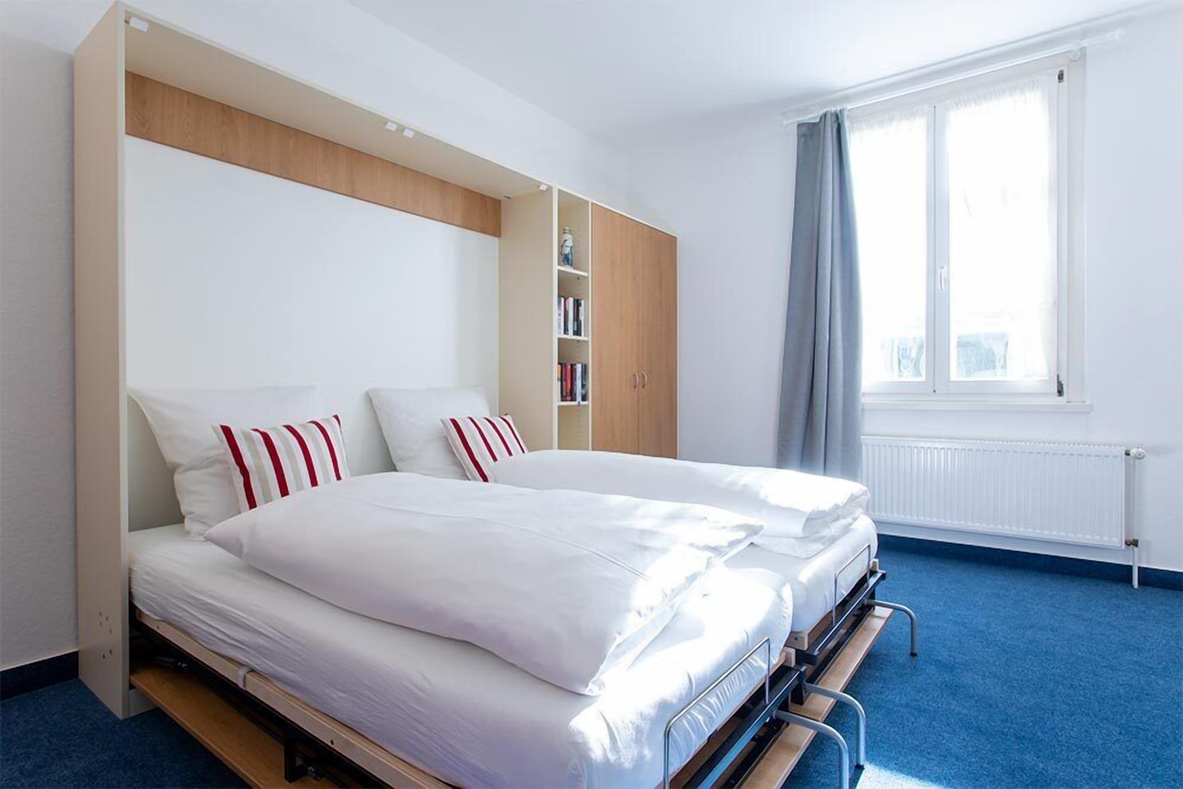 A bedroom with a bed, a wardrobe, a window, and a radiator.