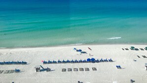 An aerial view of a beach with rows of blue umbrellas and lounge chairs, a clear blue ocean, and a sandy beach. - Spectacular 3 Bedroom, 2 Masters on the Water, amazing views, free beach chairs  (Panama City Beach)