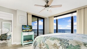 A bedroom with a bed, a ceiling fan, a television, and a view of the ocean. - Spectacular 3 Bedroom, 2 Masters on the Water, amazing views, free beach chairs  (Panama City Beach)