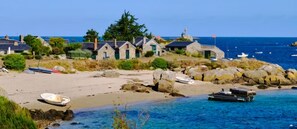 Experience the charm of les îles Chausey, where boats and traditional stone buildings meet the sandy beach.