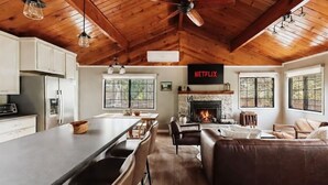 Een ruime woonkamer met een open haard, een grote eettafel en een keuken met moderne apparatuur.
