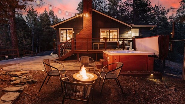 Een chalet met een open haard, terras en een hottub.