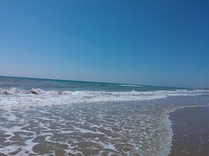 A beach with waves gently lapping at the shore under a clear blue sky. - Top apartment in urbanization La Marina, Región Alicante (Urbanización La Marina - San Fungencio)
