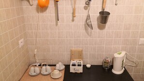 Une cuisine dotée d’un plan de travail noir, d’un coin pour préparer le thé et de divers ustensiles accrochés au mur.