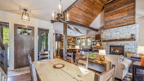 A spacious kitchen with a stone fireplace, wooden ceiling beams, and a dining area with a wooden table and chairs.