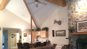 A spacious living room with a fireplace, a stone accent wall, and a ceiling fan. - Hunter Townhouse - walk to slopes!  Ski Seasonal Rental - 3BR/3BA.  Private (Hunter)