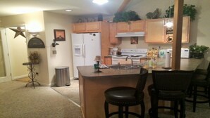 A kitchen with wooden cabinets, a refrigerator, a stove, and a sink. There are two stools and a trash can. - Hunter Townhouse - walk to slopes!  Ski Seasonal Rental - 3BR/3BA.  Private (Hunter)