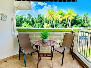 A balcony with two chairs, a small table, and a potted plant.