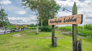 A wooden sign with 'Naturhefen Loddin' written on it, surrounded by grass and trees. - Modern vacation apartment in Loddin with garden, WLAN & barbecue - quiet, close to the beach, mod (Loddin)