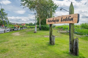 A wooden sign with 'Naturhefen Loddin' written on it, surrounded by grass and trees. - Modern vacation apartment in Loddin with garden, WLAN & barbecue - quiet, close to the beach, mod (Loddin)