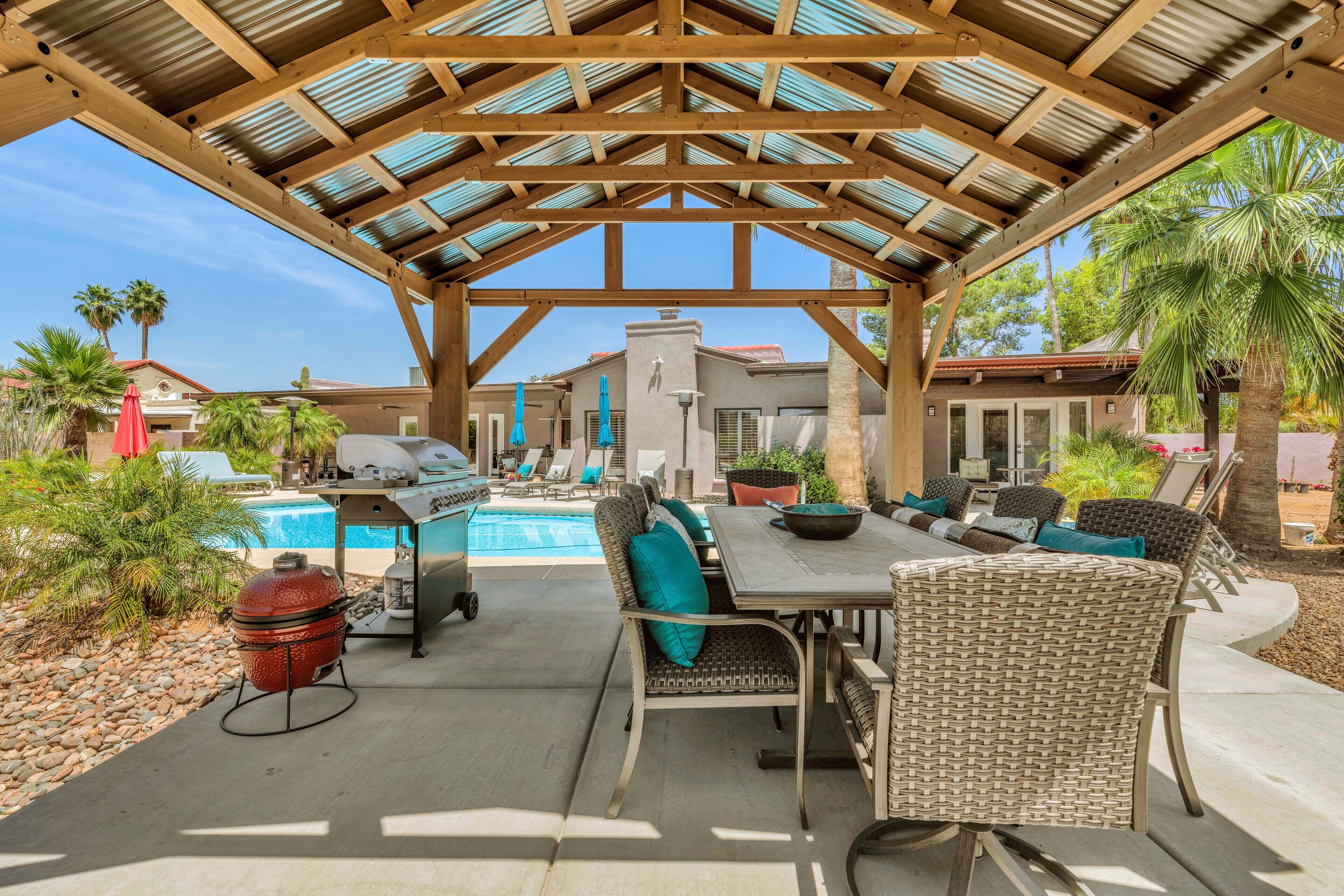 Un espace extérieur abrité comprenant une piscine, des chaises longues et un barbecue.