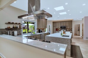 A modern kitchen with a central island, built-in appliances, and a large window providing natural light.