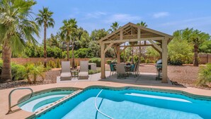 Un jardin avec une piscine, des meubles de patio et une pergola.