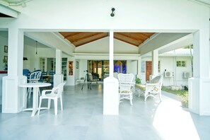 A spacious covered patio area with white furniture and a wooden ceiling.