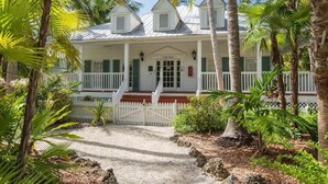 A white building with a porch, surrounded by palm trees and a gravel path. - Paradise found at the Key West Golf Club! (Key West)