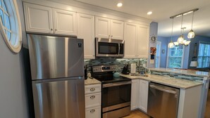 A modern kitchen with stainless steel appliances, white cabinetry, a microwave, and a built-in oven. - Paradise found at the Key West Golf Club! (Key West)