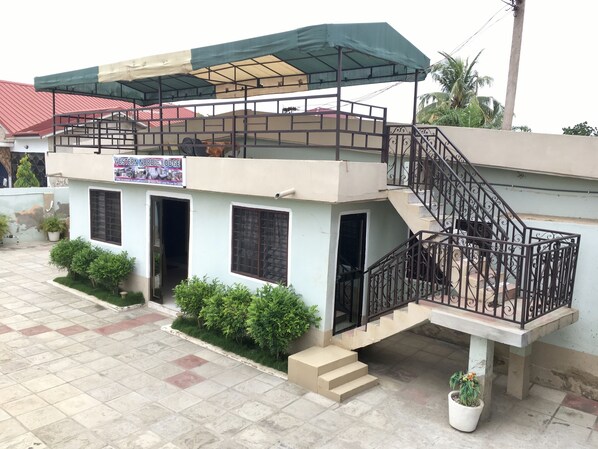 A two-story building with a sign reading "Western Nordic Lodge." It features a covered outdoor area with a staircase leading to the upper floor. - Western Nordic Lodge (Tema)