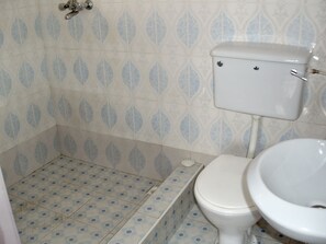 A bathroom with a toilet and sink, tiled floor with a leaf pattern, and a wall with a similar leaf design. - Western Nordic Lodge (Tema)