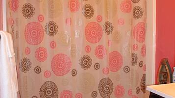 A bathroom with a patterned shower curtain, a white toilet, and a wooden floor.