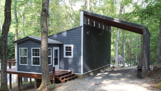Een chalet met terras, omringd door bomen.