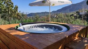 A hot tub with a wooden deck, surrounded by greenery and mountains in the background. - Cozy house in a rural setting (tenteniguada)
