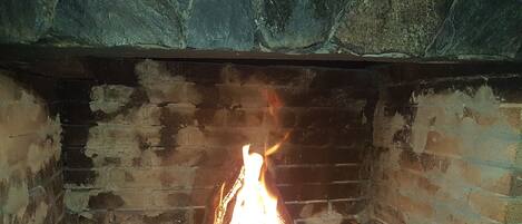 Una chimenea con fuego encendido, rodeada de paredes de ladrillo.