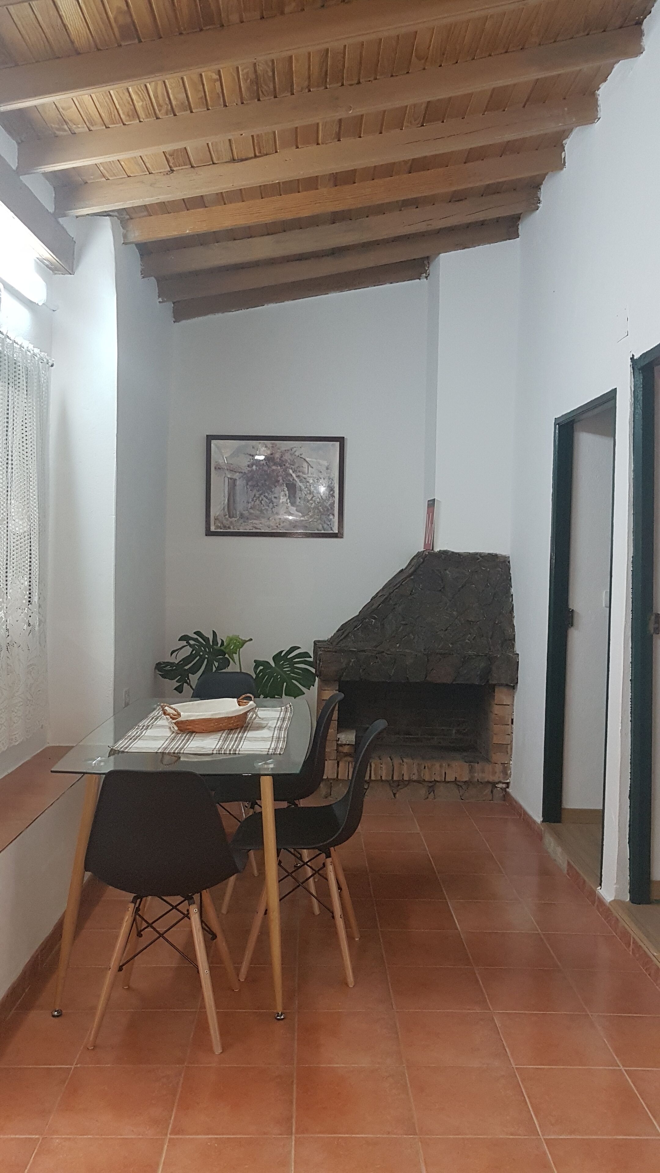 Zona pranzo con tavolo, sedie, una pianta in vaso e un camino.