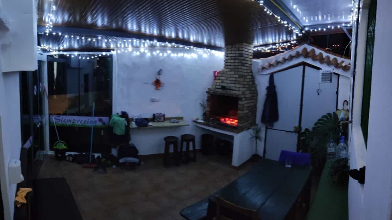 Un área de estar al aire libre acogedora, con chimenea de ladrillo, luces cálidas y una pequeña barra.