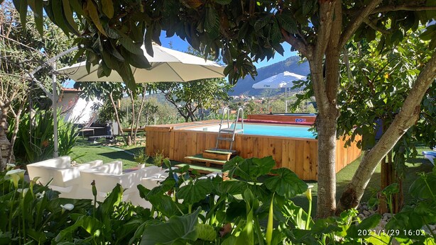 A backyard with a wooden deck, a pool, and a covered seating area. - Cozy house in a rural setting (tenteniguada)