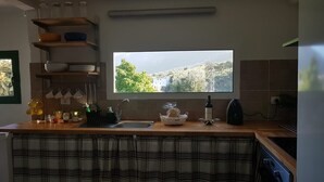 A kitchen with a window, a sink, and various kitchen items on the counter. - Cozy house in a rural setting (tenteniguada)