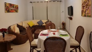 Comedor con una mesa redonda dispuesta para cuatro personas, rodeado de sillas de mimbre.