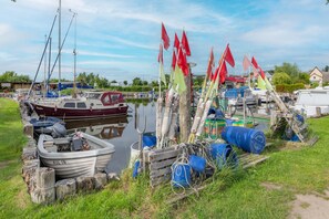 A marina with boats docked, wooden posts with flags, and scattered barrels. - Cozy vacation apartment in Loddin with garden, sauna and playground near the east (Loddin)
