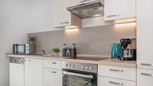 Een moderne keuken met roestvrijstalen apparatuur, een inbouwoven en een koffiezetapparaat.