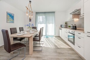 A modern kitchen with white cabinets, stainless steel appliances, and a dining area with a wooden table and chairs.