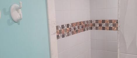 A bathroom with white tiles, a tiled shower floor, and a wall-mounted towel rack.