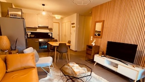 Una sala de estar moderna con un sofá, una mesa de centro y un televisor sobre un mueble blanco.